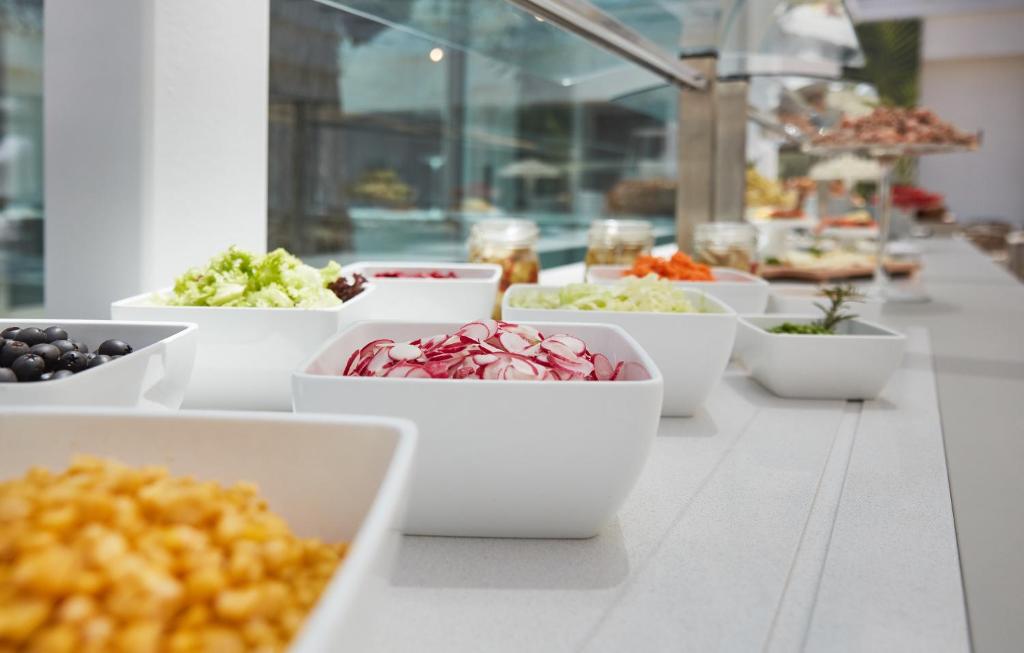 a row of white bowls of food on a table at VOI Marsa Siclà Essentia in Sampieri