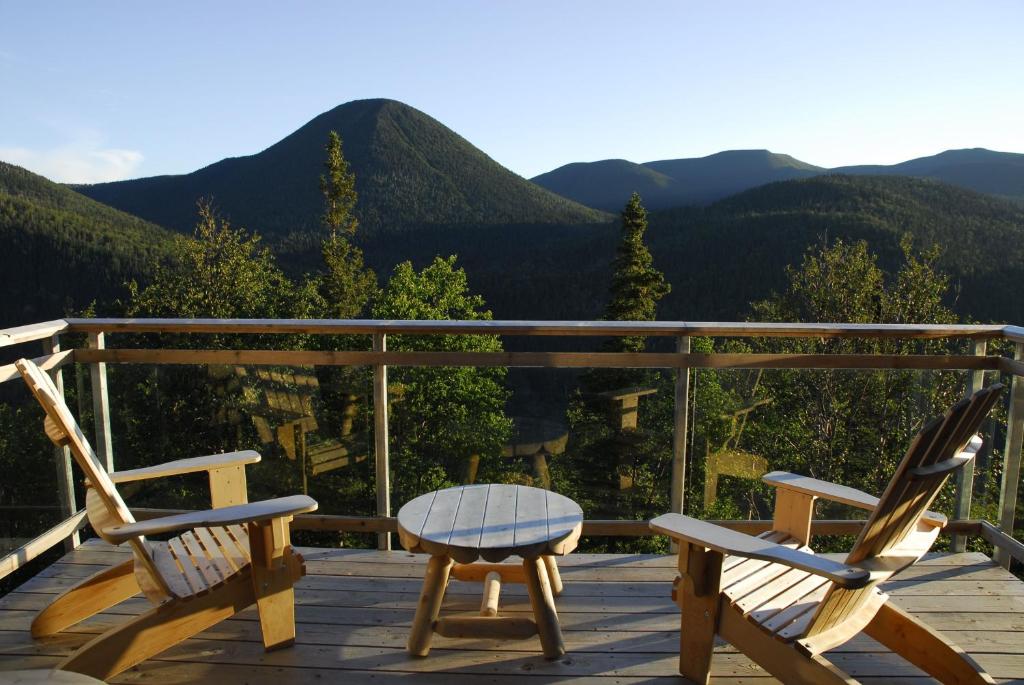 two chairs and a table on a deck with mountains at Auberge de Montagne des Chic-Chocs Mountain Lodge - Sepaq in Sainte-Anne-des-Monts