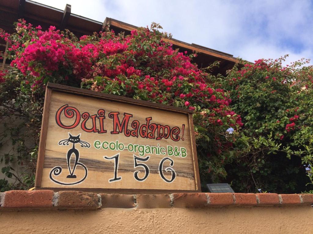 a sign for a restaurant with pink flowers on a building at B&B Oui Madame in Tijuana