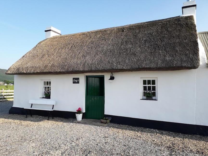 a white cottage with a thatched roof at Cissy's Cottage in Aghanloo