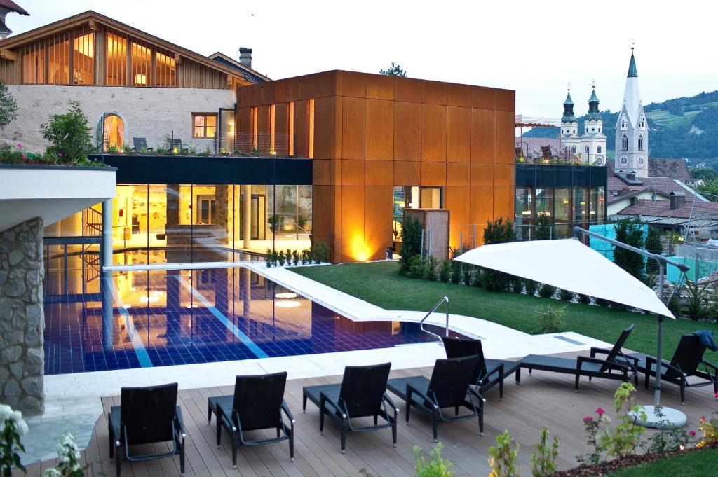 - une vue sur un bâtiment avec des chaises et une piscine dans l'établissement Hotel Grüner Baum, à Bressanone