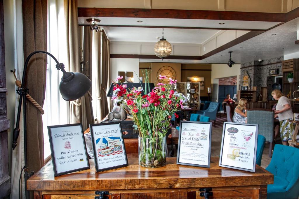 a table with a vase of flowers on it at Bacchus Hotel in Sutton on Sea