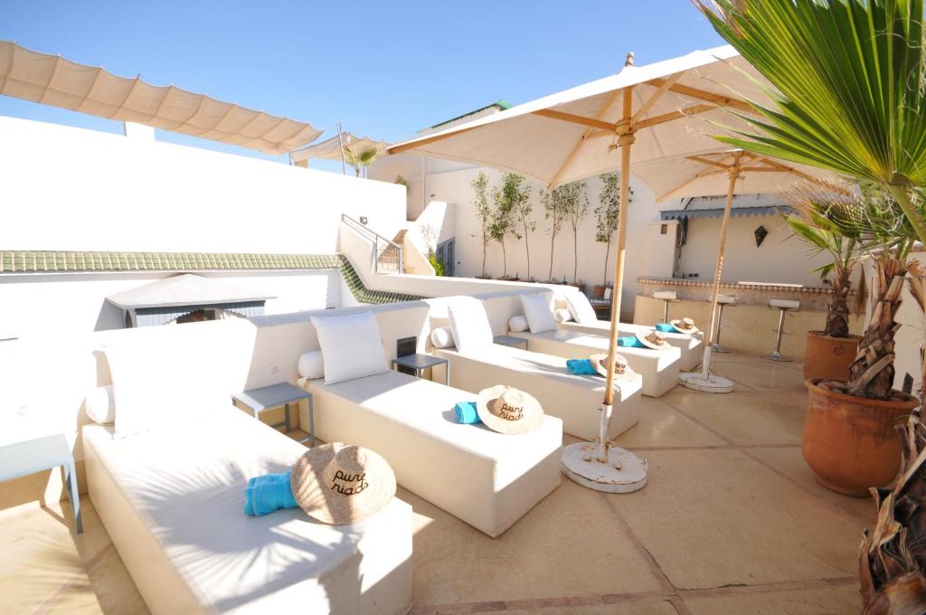 a patio with white couches and an umbrella at Riad Adore in Marrakesh