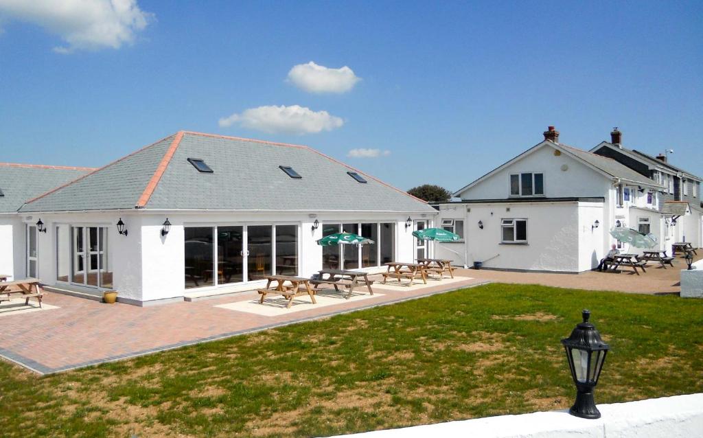 a white house with a patio and picnic tables at Newperran Holiday Park in Newquay