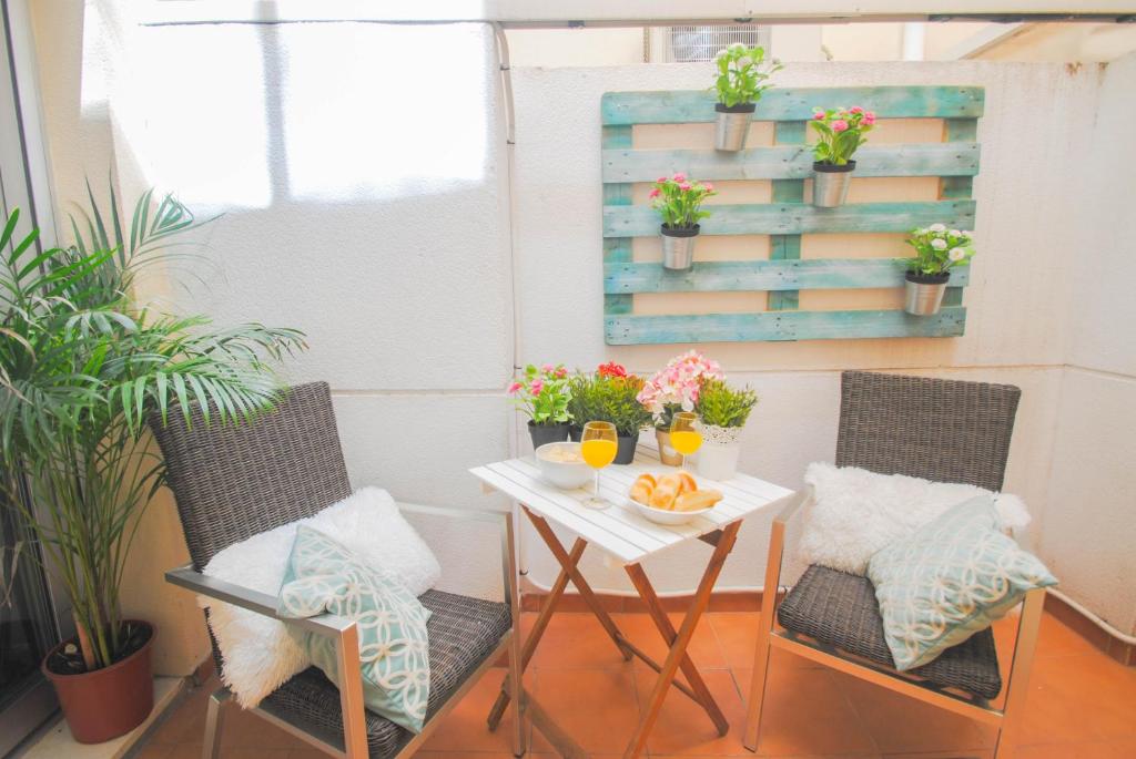 マラガにあるMalaga Center Flat Holidays Paseo de Redingのテーブル、椅子2脚、花のテーブル