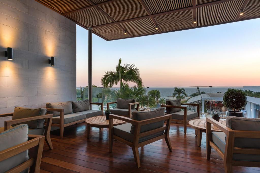 a patio with tables and chairs and a view of the ocean at Mediterranean Beach Hotel in Limassol