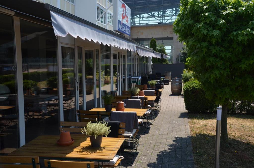 une rangée de tables et de chaises à l'extérieur d'un bâtiment dans l'établissement Pro Messe Hotel Hannover, à Hanovre