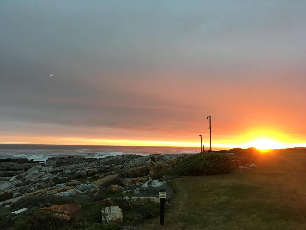 a sunset over the ocean with the sun setting at Nothing But View in Hermanus