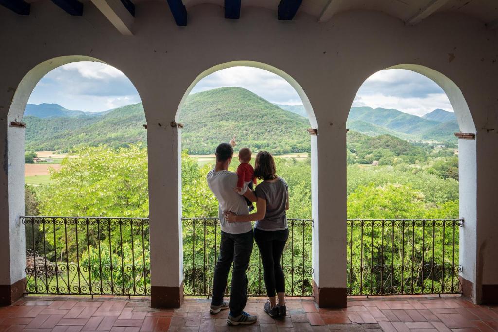 a family standing on a porch with a view of mountains at Casa Rural Mas Garganta in La Pinya