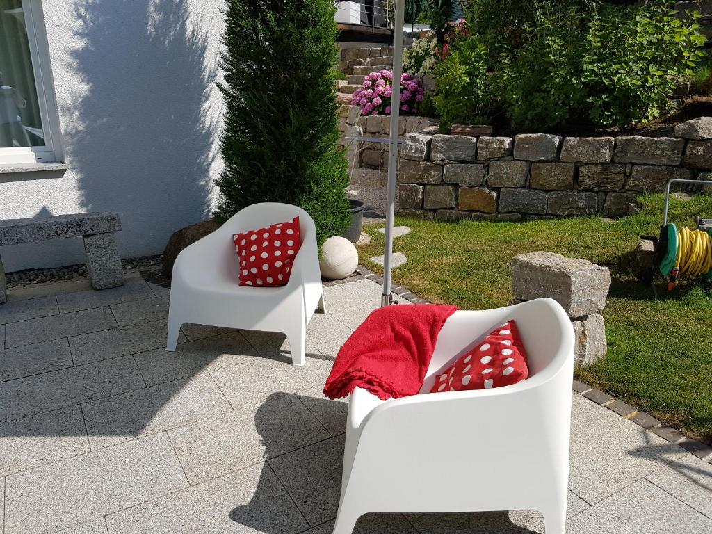 two white chairs with red pillows on a patio at Business Apartment Ravensburg - sonnig, zentral & ruhig in Ravensburg