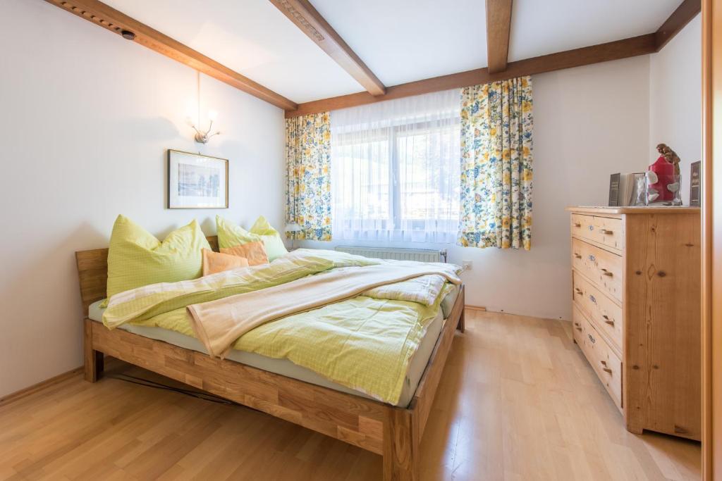 ein Schlafzimmer mit einem Bett, einer Kommode und einem Fenster in der Unterkunft Apartment Anny in Bruck an der Großglocknerstraße
