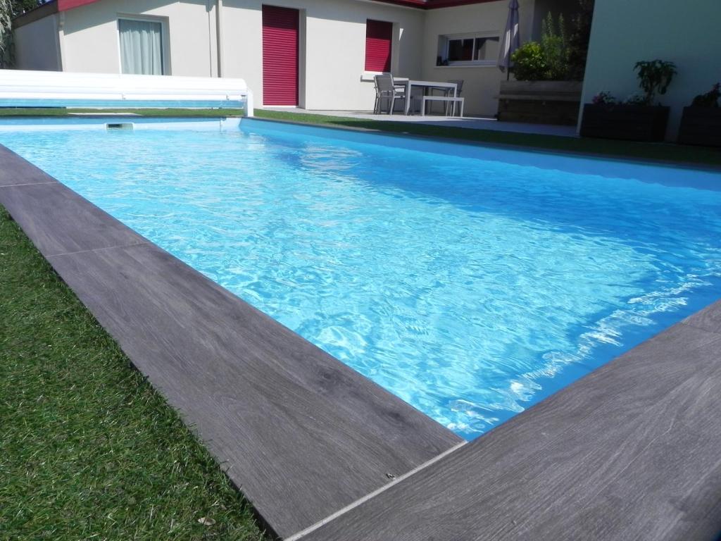 a swimming pool with blue water in a yard at La clé de vos Rêves in Orthevielle
