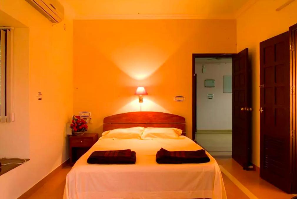 ein Schlafzimmer mit einem großen weißen Bett und einer orangefarbenen Wand in der Unterkunft Villa Brook Heritage Home in Alappuzha