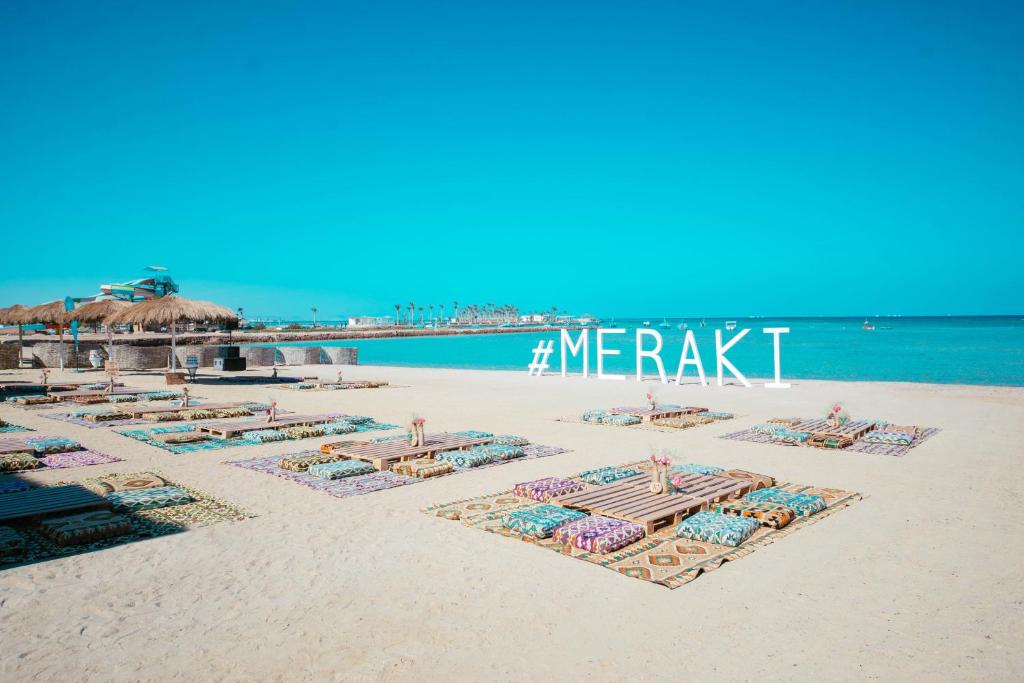 Meraki Resort - Adults Only في الغردقة: شاطئ فيه كراسي ومظلات على الرمال