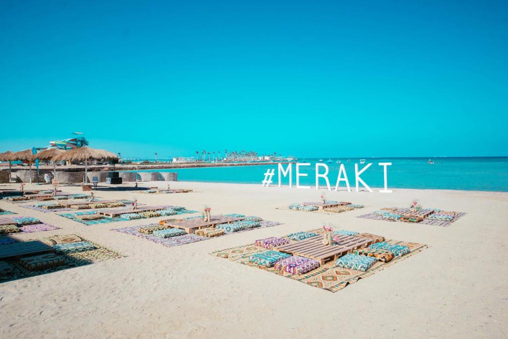 una playa con sillas y sombrillas en la arena en Meraki Resort - Adults Only en Hurghada