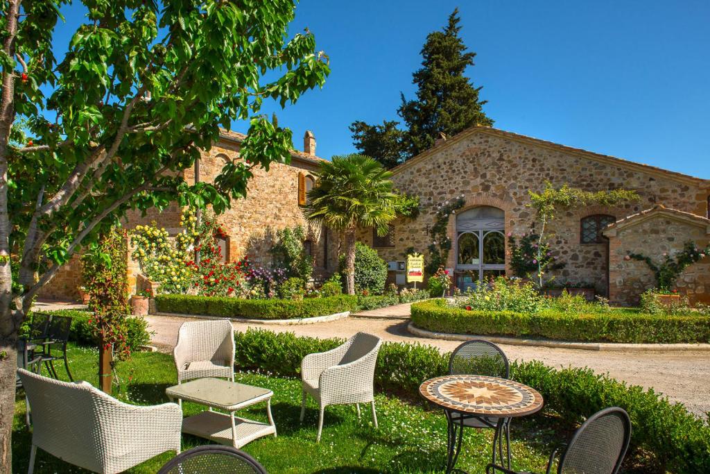 einen Garten mit Stühlen und Tischen vor einem Gebäude in der Unterkunft Castello di Spedaletto da Laura in Pienza