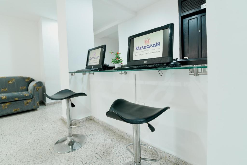a room with two chairs and a tv on a shelf at Hotel Arawak Upar in Valledupar