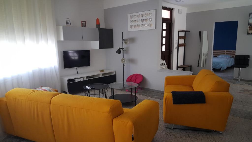 a living room with two yellow couches and a tv at Villa Tramontane in Le Grau-du-Roi
