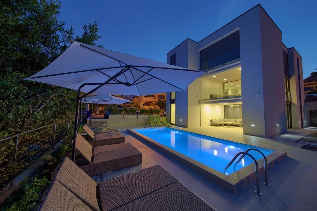 - une piscine avec un parasol à côté d'une maison dans l'établissement Villa Celeia, à Krk