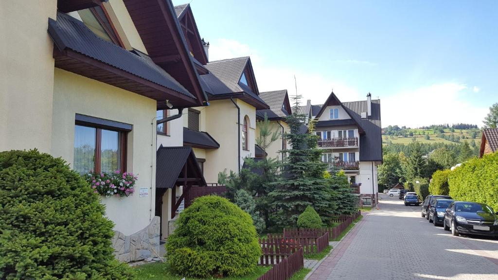 a row of houses with cars parked on a street at ZAKOgiewont in Zakopane