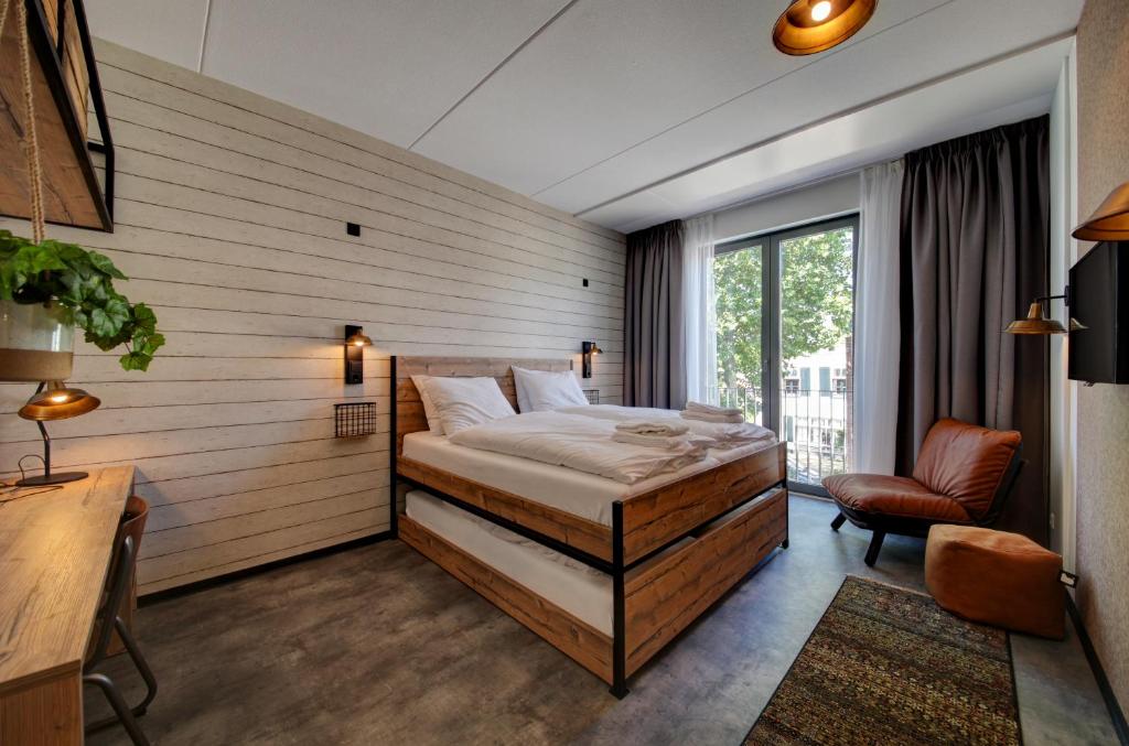 een slaapkamer met een bed en een stoel in een kamer bij GuestHouse Hotel Kaatsheuvel-Waalwijk in Kaatsheuvel