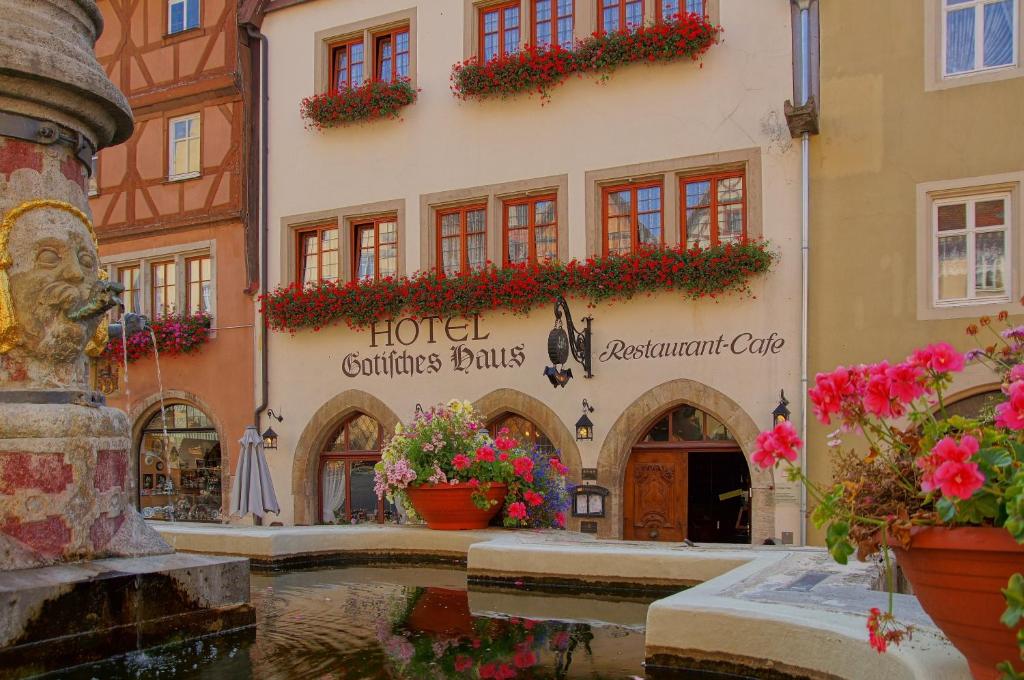 un bâtiment avec des fleurs devant une fontaine dans l'établissement Historik Hotel Gotisches Haus garni, à Rothenburg ob der Tauber