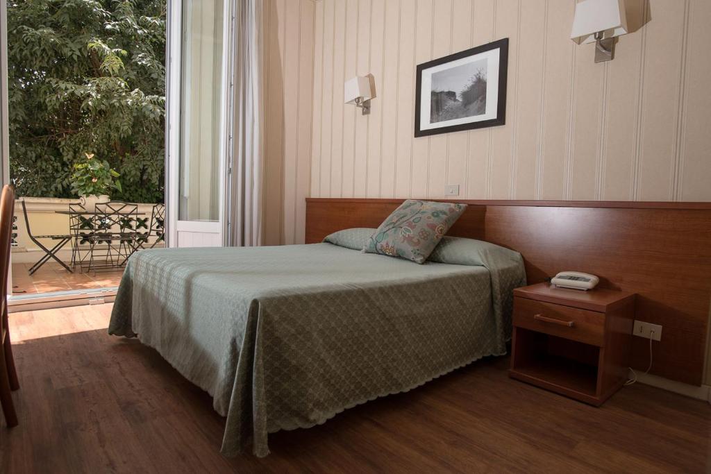 a bedroom with a bed and a table and a window at Hotel Villa Delle Rose in Rome