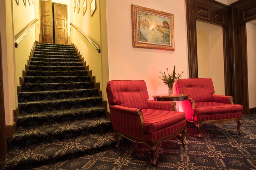 a staircase with two red chairs and a table and stairs at Hotel Villa Delle Rose in Rome