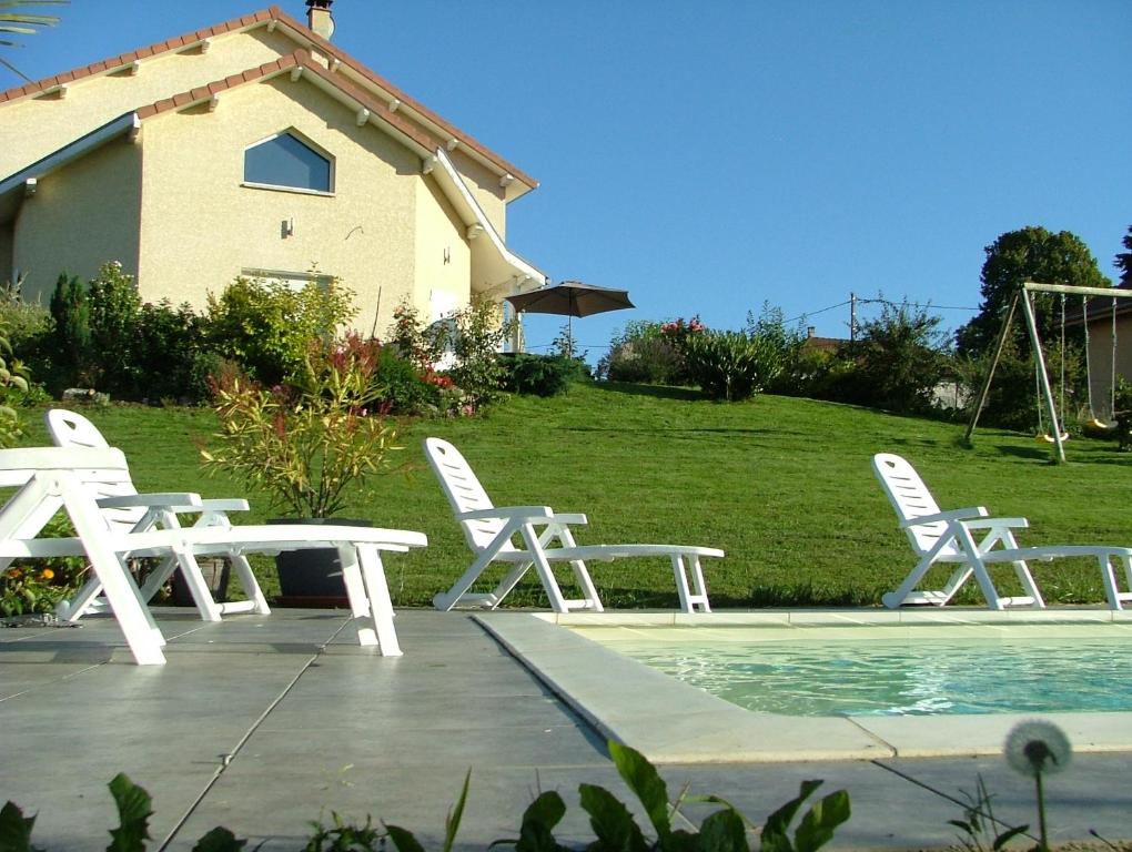 a group of white tables and chairs next to a pool at Les Enselmes in Montagnieu