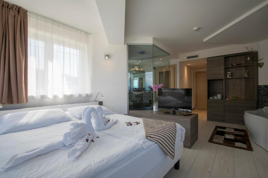 a bedroom with a large white bed and a television at Hotel Luna Bianca Folgaria in Folgaria