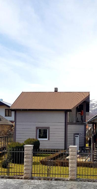 a white house with a brown roof and a fence at Guest house Vlahovic in Kolašin