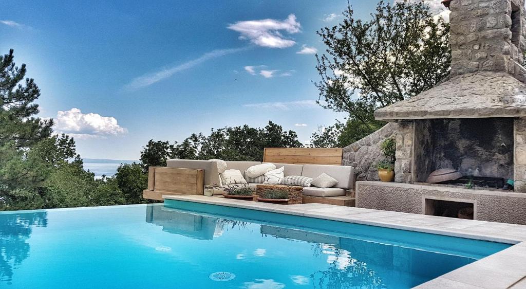 a swimming pool with a couch and a fireplace at Villa Sea View in Veprinac