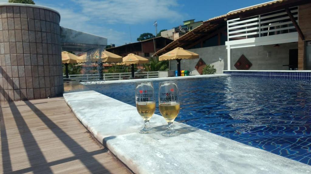 two glasses of wine sitting next to a swimming pool at Pipa's Bay - Flats para temporada in Pipa
