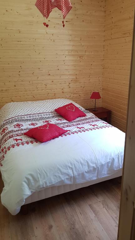 ein Schlafzimmer mit einem Bett mit roten Kissen darauf in der Unterkunft F2 SUR LES HAUTEURS DE GERARDMER in Gérardmer