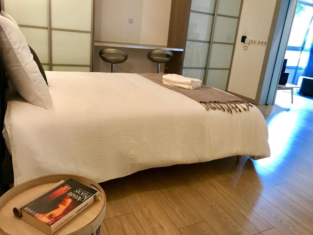 Una cama blanca con una mesa con un libro. en Petit loft Drouot, en Nancy