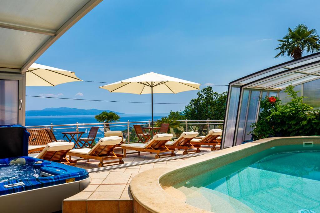 a swimming pool with chairs and an umbrella at Villa Roses Apartments & Wellness in Ičići