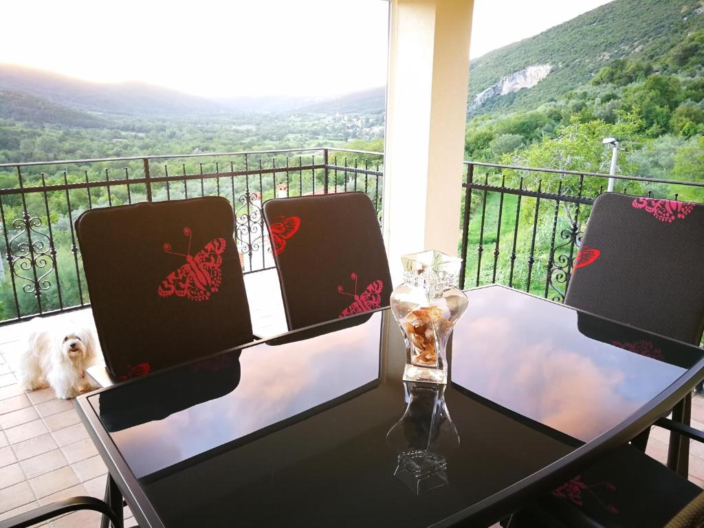 una mesa con 2 sillas y un perro en el balcón en Apartma Čeh en Gabrovica pri Črnem Kalu