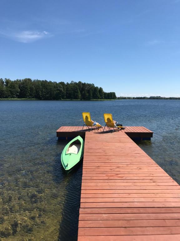 eine Anlegestelle mit zwei Stühlen und einem Boot auf dem Wasser in der Unterkunft Six Island House in Czarnówka