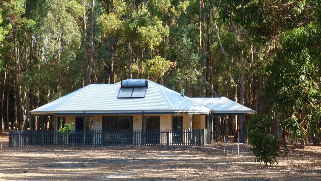 a house with a tin roof in front of trees at Margaret River Hideaway & Farmstay in Margaret River Town