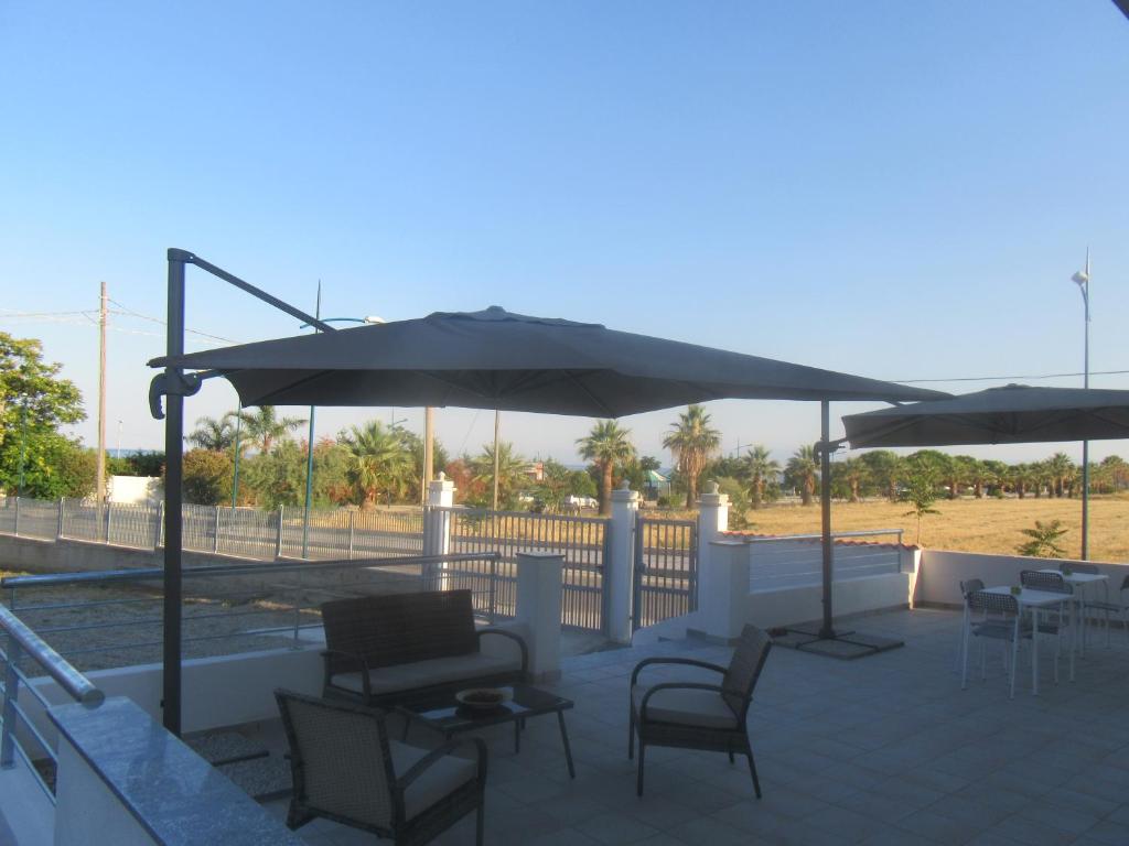 un patio con mesas, sillas y sombrillas en Il Sogno di Calipso, en Amendolara