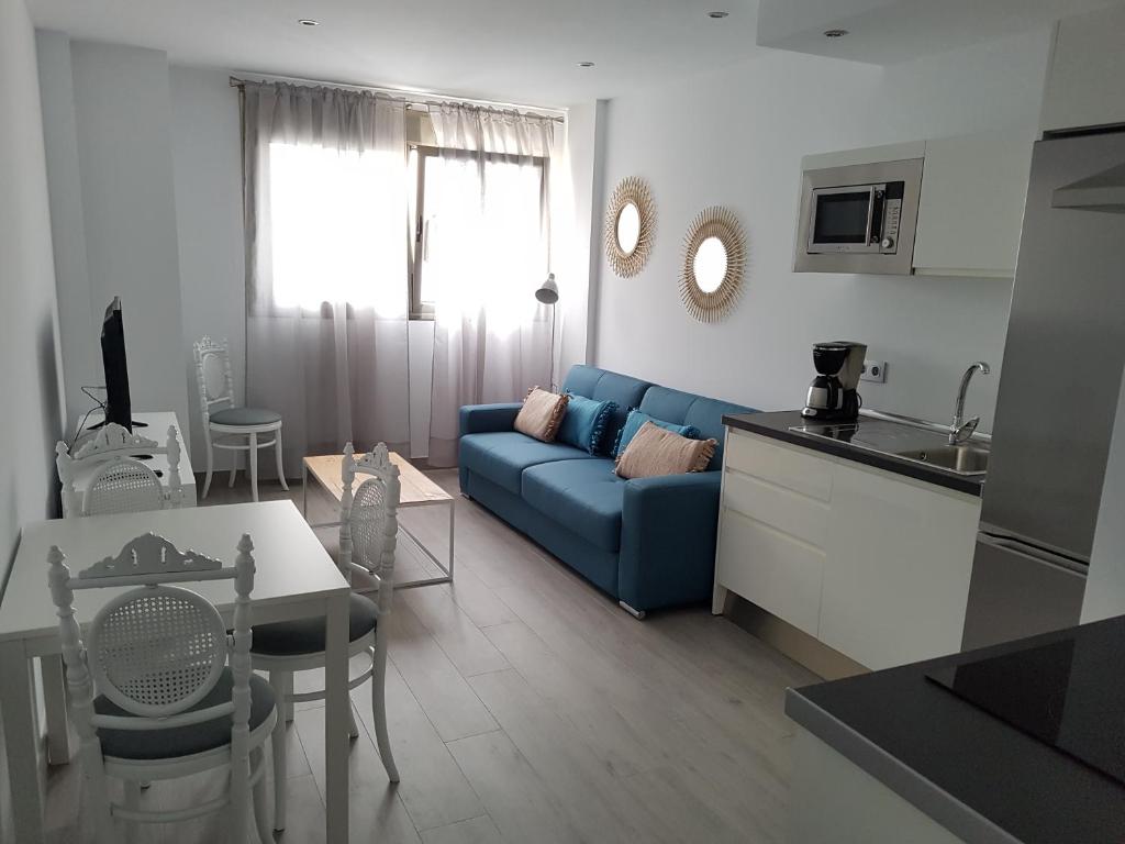 ein Wohnzimmer mit einem blauen Sofa und einer Küche in der Unterkunft RK City Center in Las Palmas de Gran Canaria
