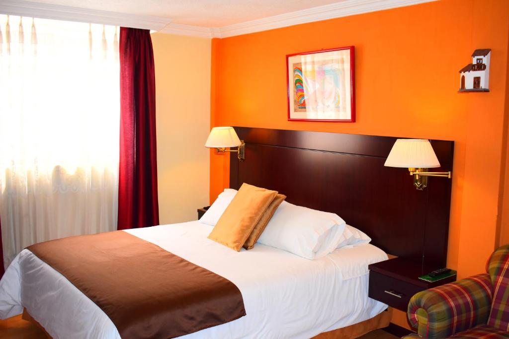 1 dormitorio con 1 cama con pared de color naranja en Endamo Hotel, en Latacunga