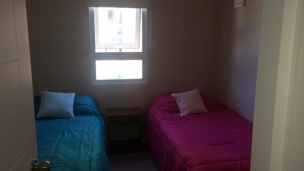 two beds in a small room with two windows at Departamento Viña del Mar in Viña del Mar