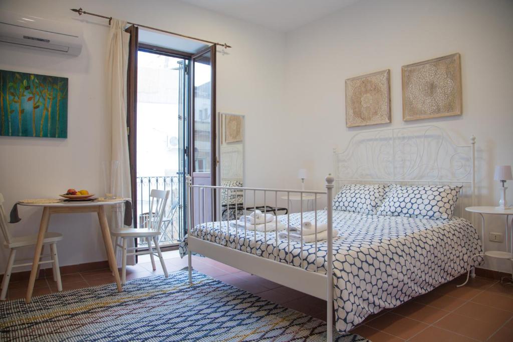 a bedroom with a bed and a table and a balcony at Casa Miele Ortigia in Syracuse