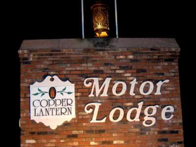a brick wall with a sign for a motor lodge at Copper Lantern Motor Lodge in West Brookfield