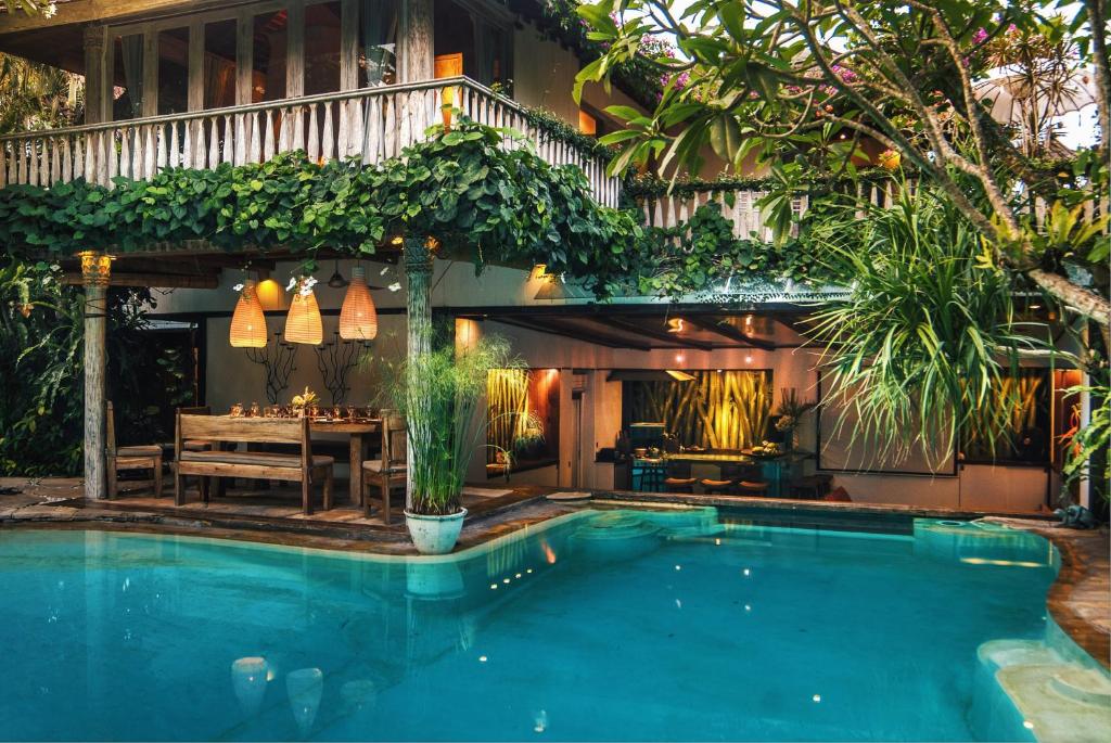 a pool in front of a house with a dining table at Villa Istimewa in Seminyak