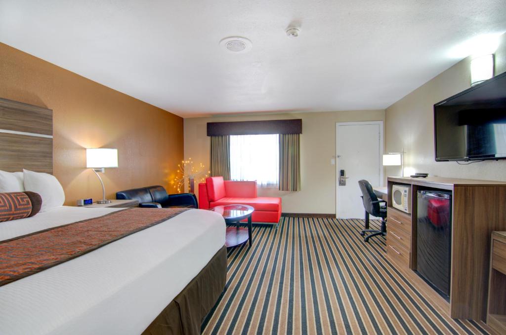 a hotel room with a bed and a living room at Westbridge Inn & Suites in Clinton
