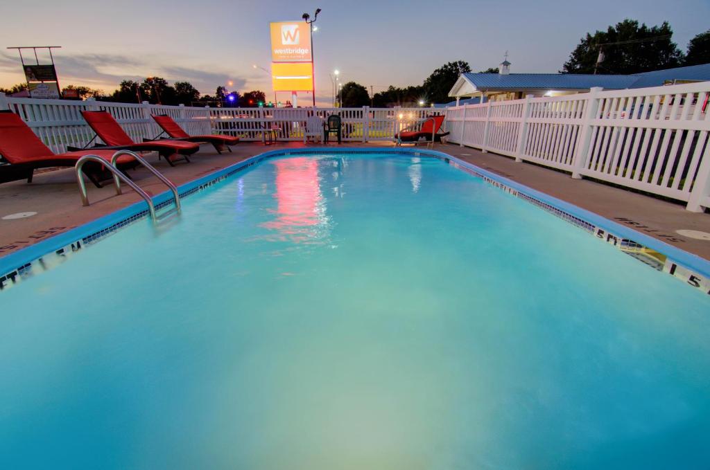 a large swimming pool with chairs and a fence at Westbridge Inn & Suites in Clinton