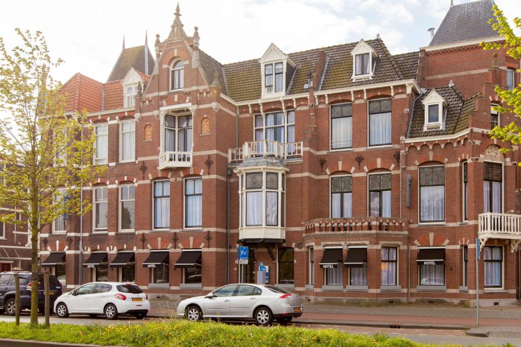 twee auto's geparkeerd voor een bakstenen gebouw bij Best Western Hotel Den Haag in Den Haag