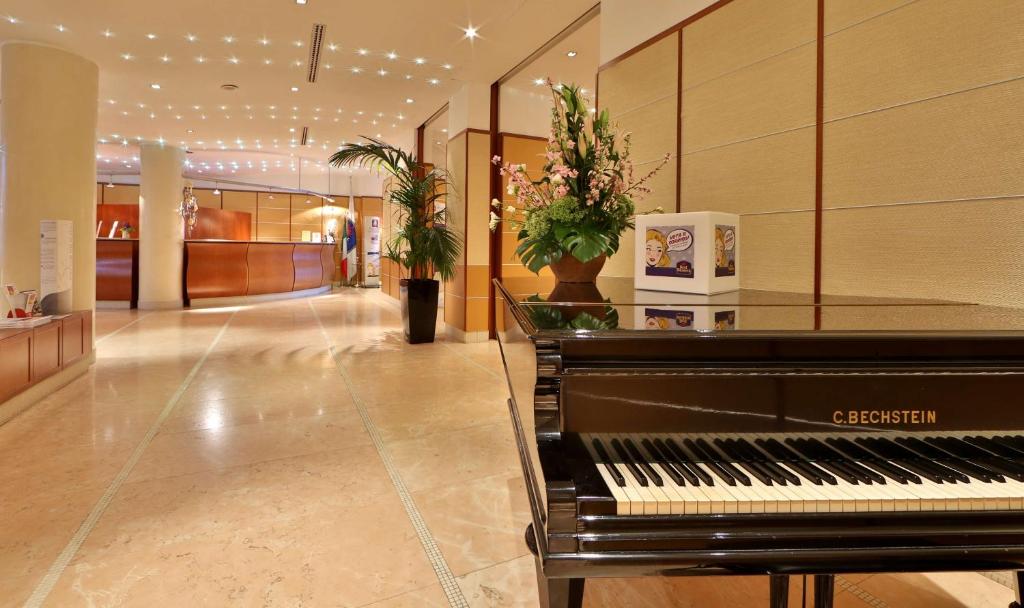 a lobby with a piano in the middle of a building at Hotel Cappello D'Oro, BW Signature Collection in Bergamo